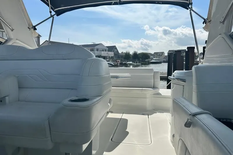 Slide: The Image of 2004 Formula 330 Sun Sport boat interior with white seating, docked near waterfront homes. - 15