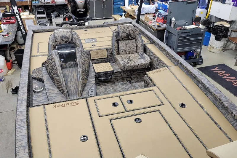Slide: The Image of 2026 Xpress H20C Crappie boat interior with camo seats and Yamaha engine in workshop. - 8