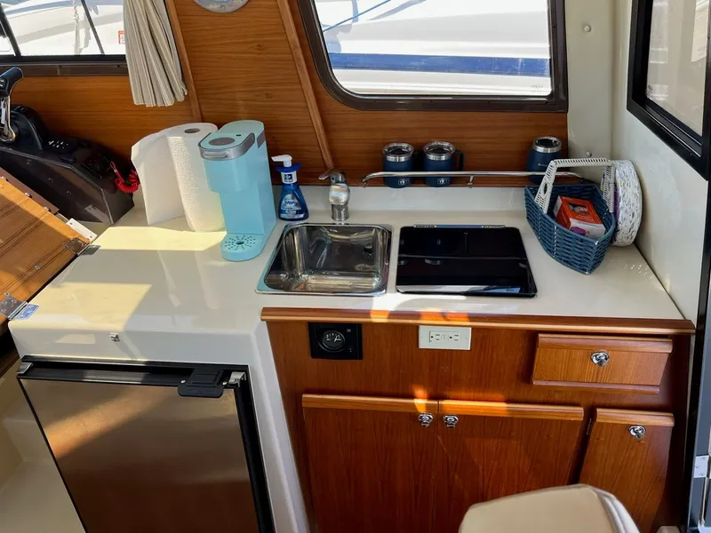 Slide: The Image of 2020 Ranger Tugs R-25 interior kitchenette with sink, stove, and storage. - 27
