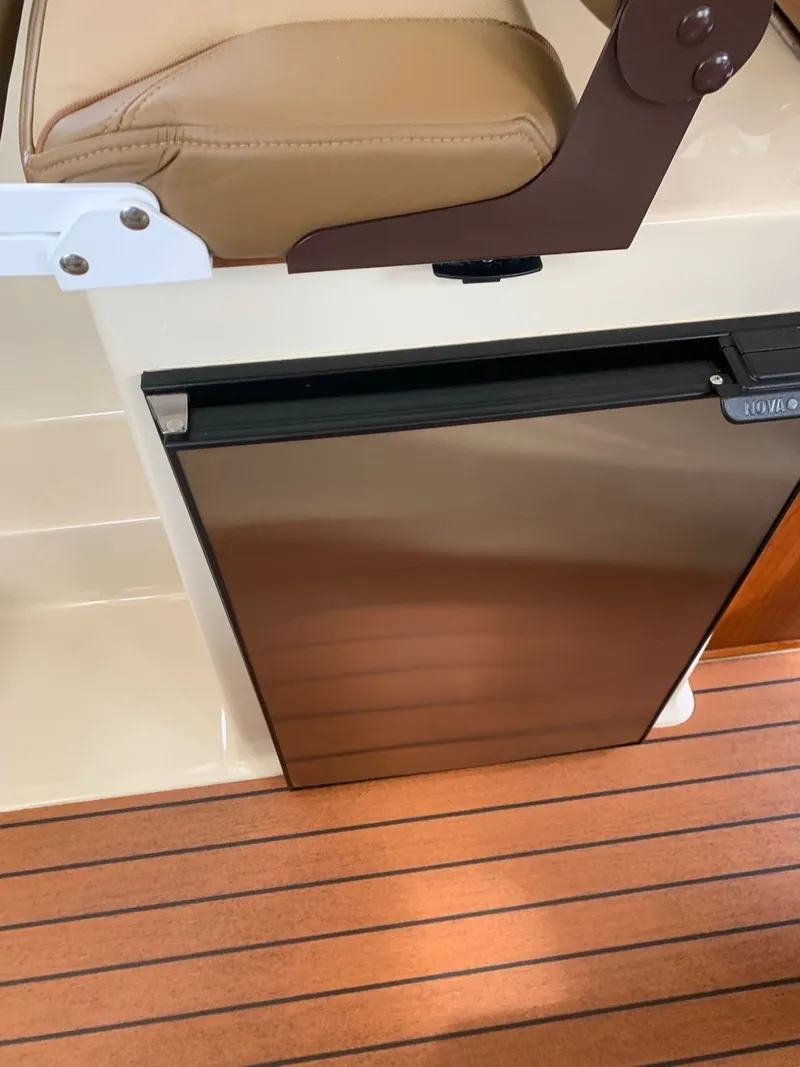 Slide: The Image of Ranger Tugs R-25 2020 interior with beige seat and stainless steel fridge. - 31