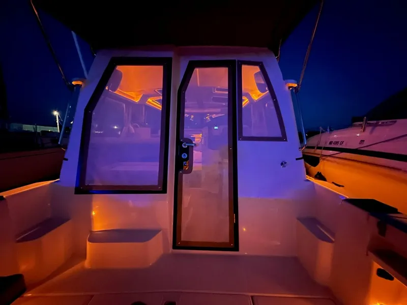 Slide: The Image of 2020 Ranger Tugs R-25 boat interior illuminated at night with vibrant orange lighting. - 39