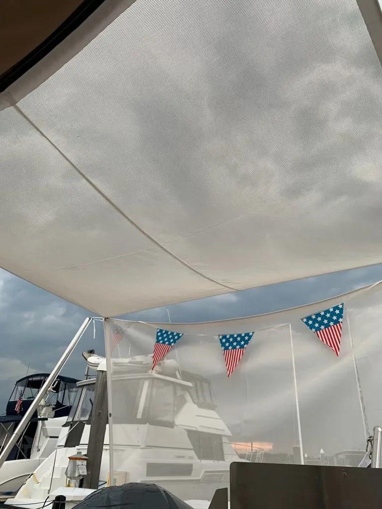 Slide: The Image of American flag bunting decorates a Ranger Tugs R-25 boat, 2020 model, under a cloudy sky. - 43