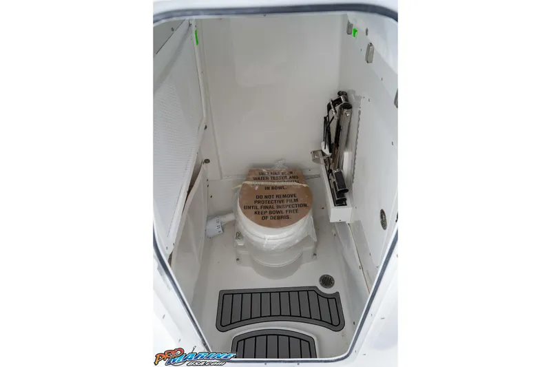 Slide: The Image of Interior of 2026 Sea Hunt Ultra 265 SE boat, featuring a compact marine toilet. - 32
