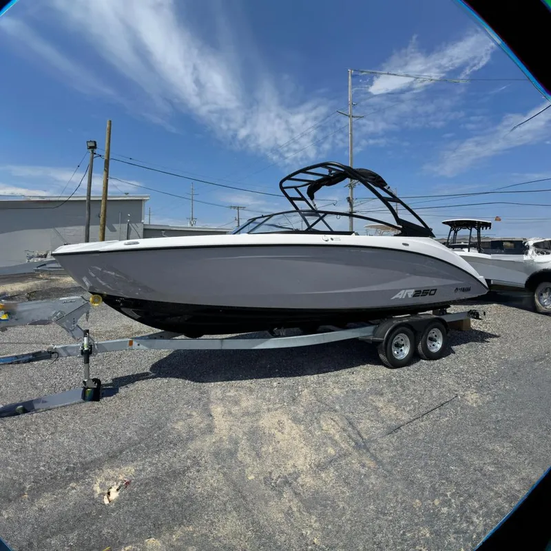The Image of 2026 Yamaha Boats AR250 on trailer, sleek design, gray and white exterior, parked outdoors. - 0
