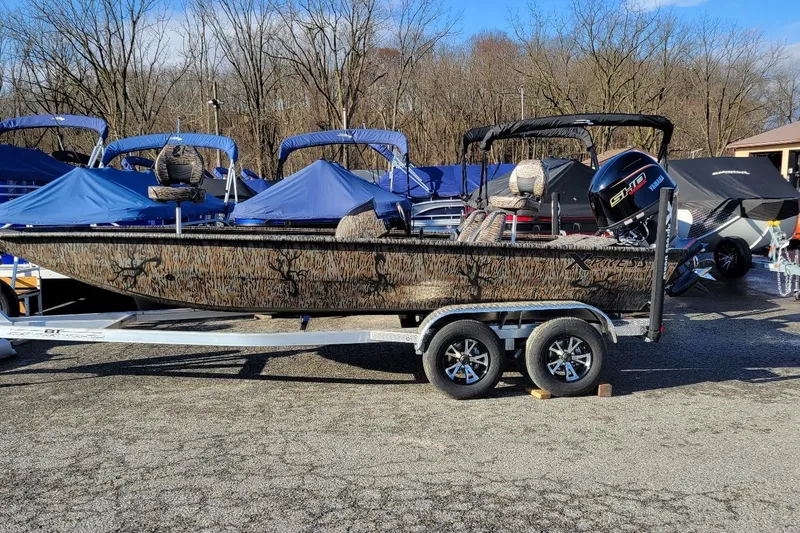 The Image of 2026 Xpress XP200 Catfish boat on trailer, camo design, parked outdoors. - 1