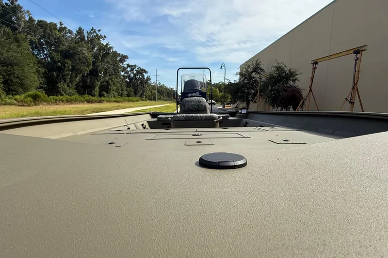 Slide: The Image of 2026 Tracker Grizzly 2072 CC boat, outdoor view, surrounded by trees and a building. - 3