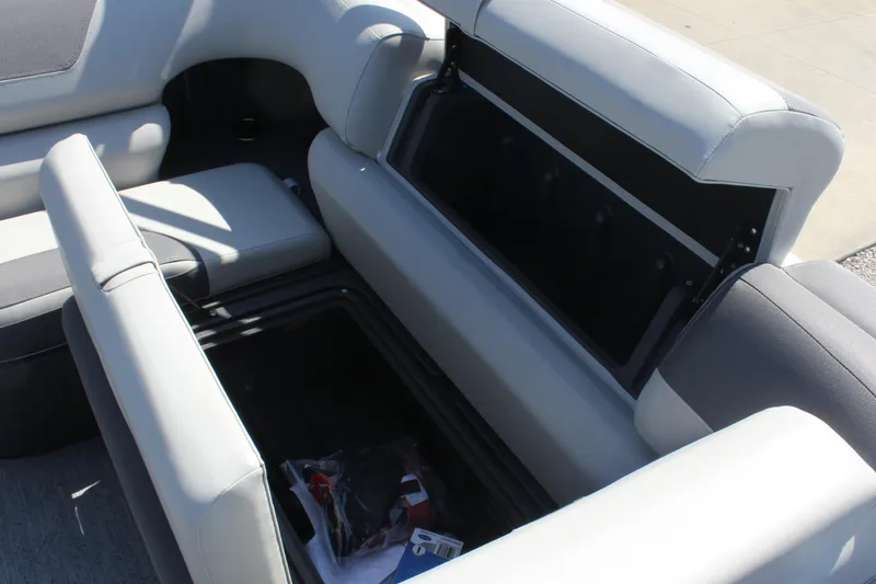 Slide: The Image of 2026 Sun Tracker Fishin' Barge 20 DLX storage compartment with open seat and visible contents. - 14