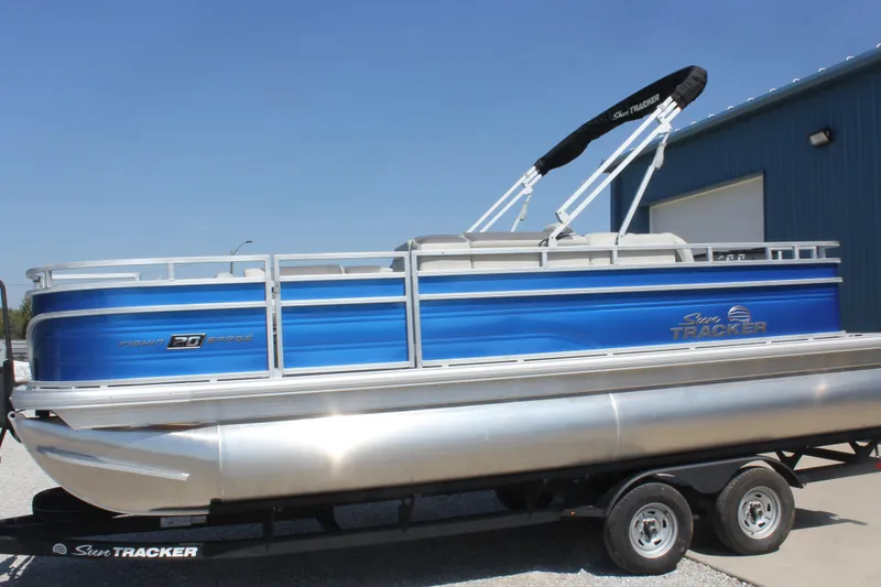 Slide: The Image of 2026 Sun Tracker Fishin' Barge 20 DLX pontoon boat with blue exterior on trailer. - 3