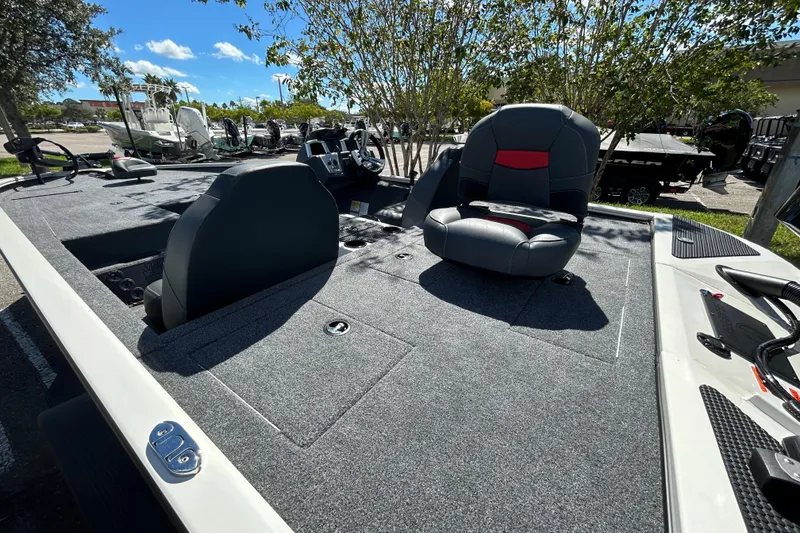 Slide: The Image of 2025 Tracker Savage 215 boat interior with seating and control panel, parked outdoors. - 8