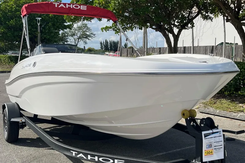 Slide: The Image of 2026 Tahoe T18 boat with red canopy on trailer, parked outdoors. - 6