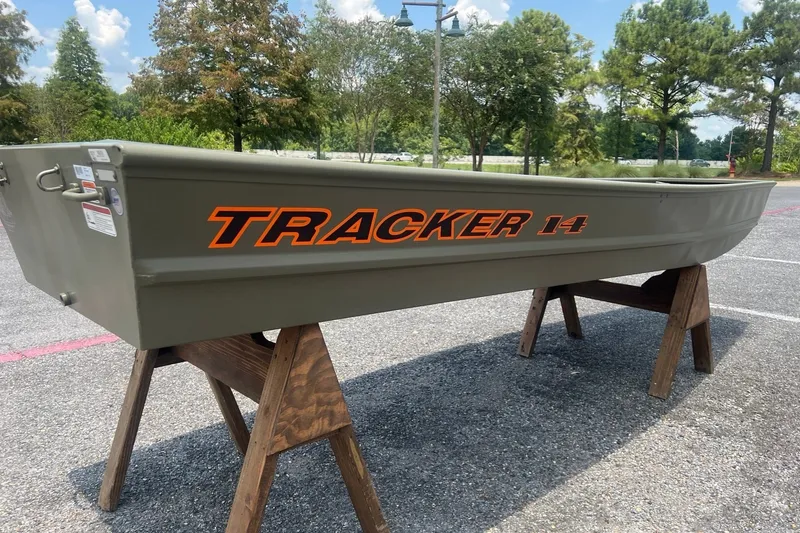 The Image of 2026 Tracker Grizzly 14 Jon boat displayed outdoors on wooden stands. - 0