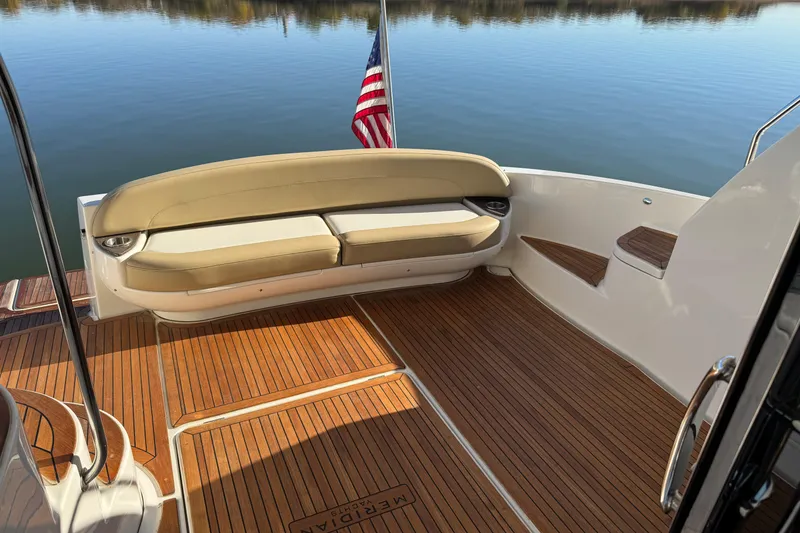 Slide: The Image of 2016 Meridian 441 yacht deck with seating, wooden flooring, and American flag. - 65