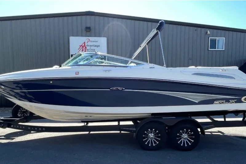 Slide: The Image of 2007 Sea Ray 250 SLX boat on trailer, parked outside marine service building. - 1