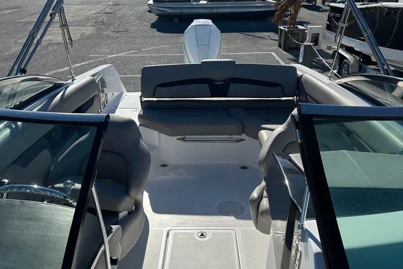 Slide: The Image of 2022 Four Winns HD5 OB boat interior with seating and windshield, parked outdoors. - 11