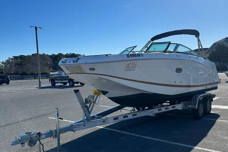 Slide: The Image of 2022 Four Winns HD5 OB boat on trailer in parking lot under clear blue sky. - 4