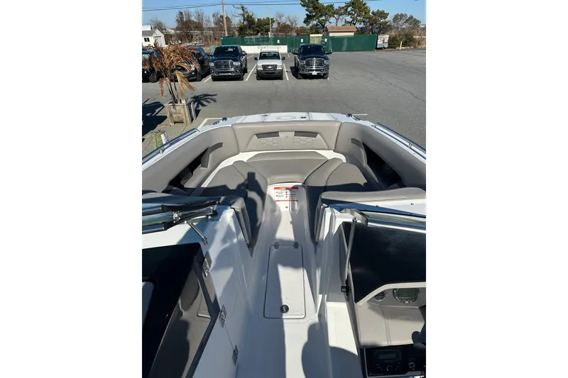 Slide: The Image of 2022 Four Winns HD5 OB boat interior with seating, parked cars in background. - 9
