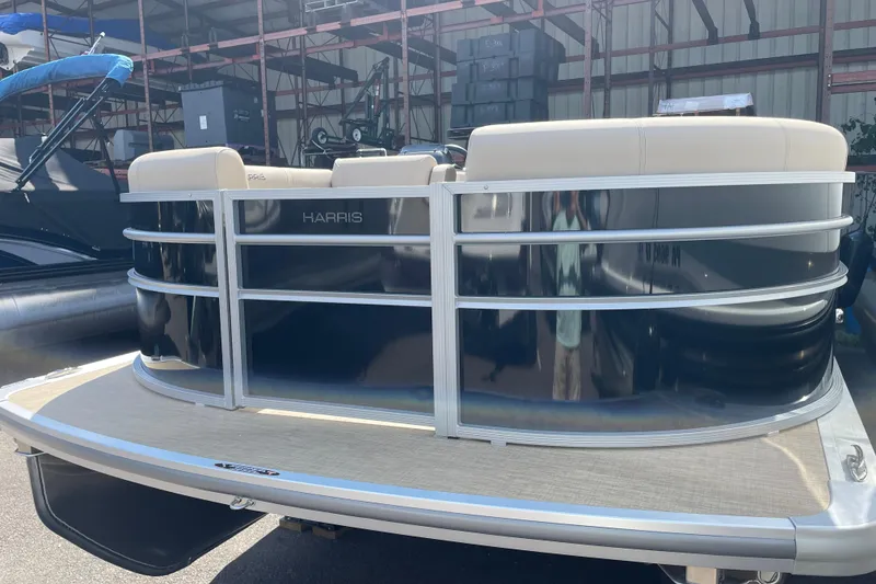 Slide: The Image of 2026 Harris Cruiser 210 CW pontoon boat with sleek design in a storage facility. - 1