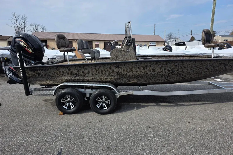 The Image of 2026 Xpress H22B Bay boat on trailer, featuring camouflage design and powerful outboard motor. - 0