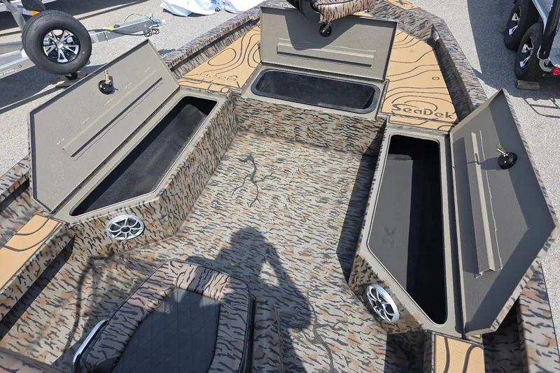 Slide: The Image of 2026 Xpress H22B Bay boat interior with open storage compartments and camouflage design. - 16