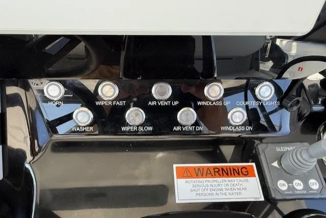 Slide: The Image of Control panel of 2026 Wellcraft 38 T-Top boat with various switches and warning label. - 18