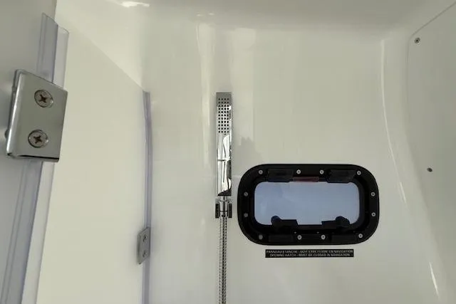 Slide: The Image of Interior view of 2026 Wellcraft 38 T-Top boat, featuring a showerhead and porthole. - 35