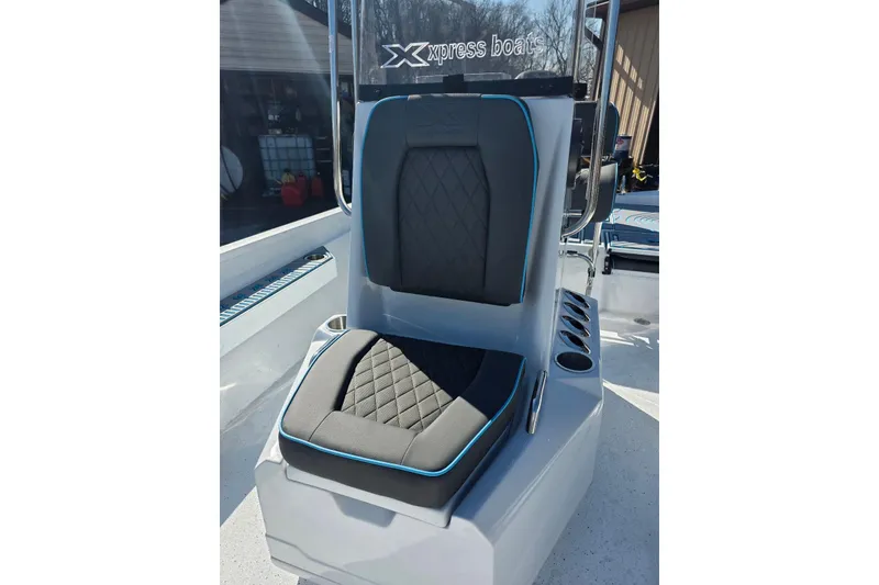 Slide: The Image of 2026 Xpress H22B Bay boat seat with black and blue trim, cup holders visible. - 20