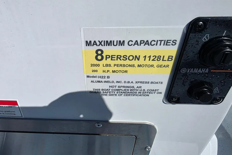 Slide: The Image of 2026 Xpress H22B Bay boat capacity label, 8 persons, 1128 lbs, Yamaha controls visible. - 27