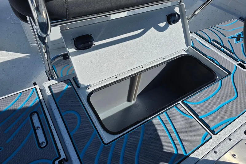 Slide: The Image of Open storage compartment on 2026 Xpress H22B Bay boat with blue patterned flooring. - 29