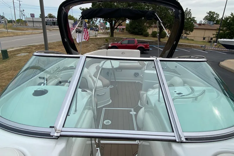 Slide: The Image of 2015 Crownline 305 SS boat with open cockpit and windshield, parked outdoors. - 12