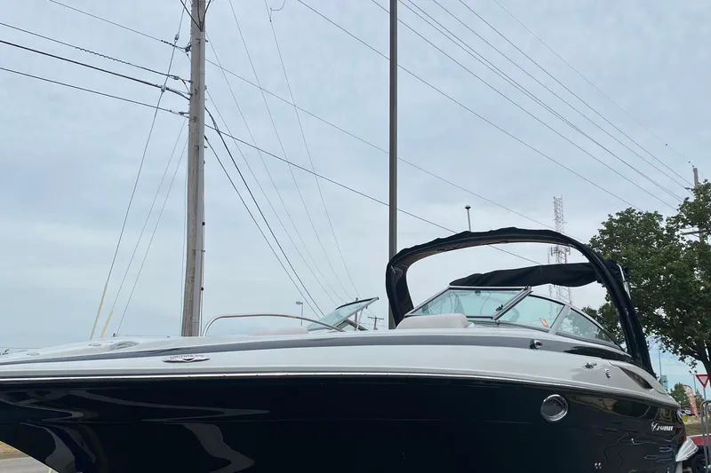 Slide: The Image of 2015 Crownline 305 SS boat with sleek design, parked outdoors under cloudy sky. - 3