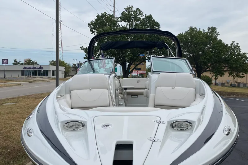 Slide: The Image of 2015 Crownline 305 SS boat with open seating, parked near a road. - 4