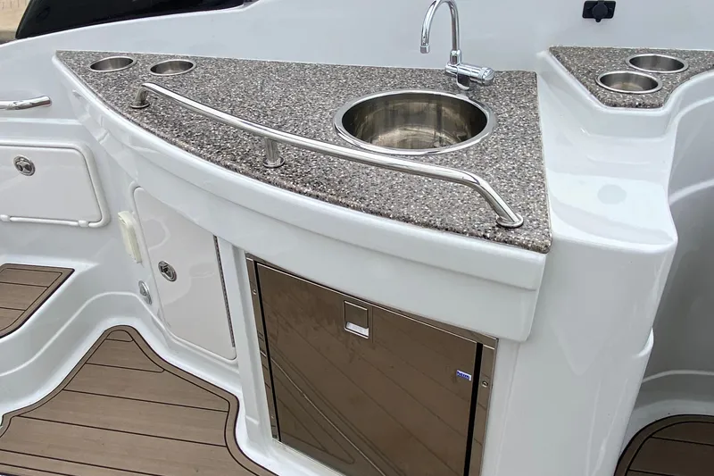 Slide: The Image of 2015 Crownline 305 SS boat kitchenette with sink, countertop, and storage. - 7