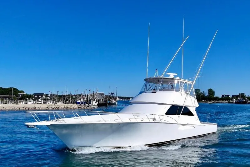 The Image of 2006 Viking 56 Convertible yacht cruising on a sunny day near a marina. - 1