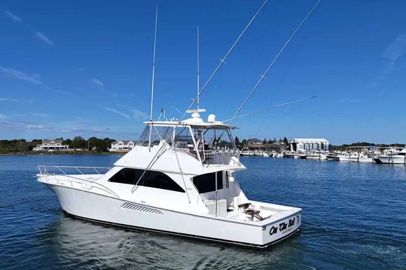 Slide: The Image of 2006 Viking 56 Convertible yacht cruising in a scenic marina under a clear blue sky. - 10
