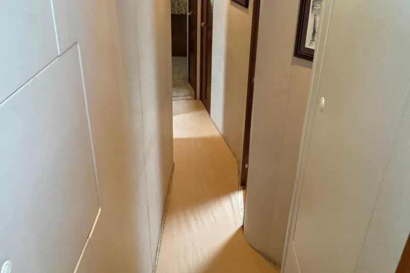 Slide: The Image of Hallway inside 2006 Viking 56 Convertible yacht, featuring beige carpet and framed artwork. - 22