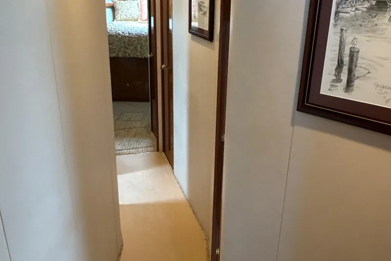 Slide: The Image of Hallway inside 2006 Viking 56 Convertible yacht, featuring framed artwork and bedroom view. - 23