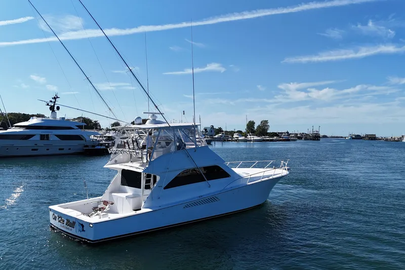 Slide: The Image of 2006 Viking 56 Convertible yacht docked in a serene marina under a clear blue sky. - 4