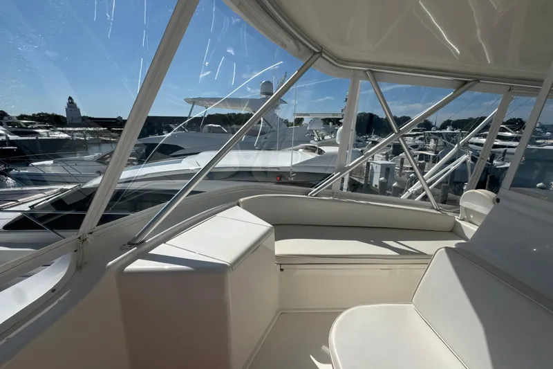 Slide: The Image of 2006 Viking 56 Convertible yacht interior with marina view, featuring sleek white seating. - 83