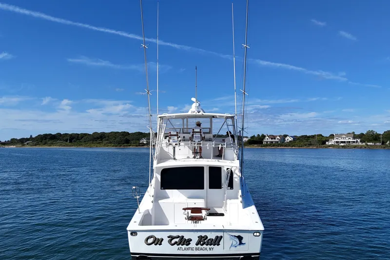 Slide: The Image of 2006 Viking 56 Convertible boat on water, clear sky, coastal homes in background. - 9