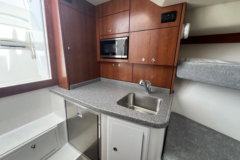 Slide: The Image of 2024 Albemarle 30 Express interior with kitchenette, featuring wood cabinets, sink, and microwave. - 11