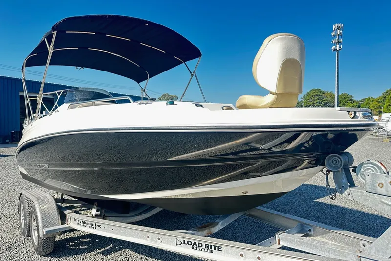 Slide: The Image of 2016 Stingray 192SC boat on trailer with canopy, parked outdoors under clear blue sky. - 1