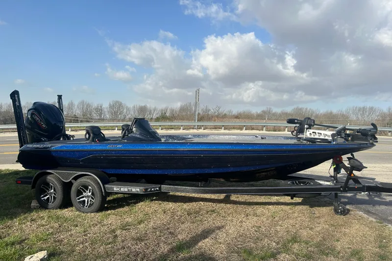 The Image of 2025 Skeeter ZXR21 boat on trailer, parked roadside under cloudy sky. - 0