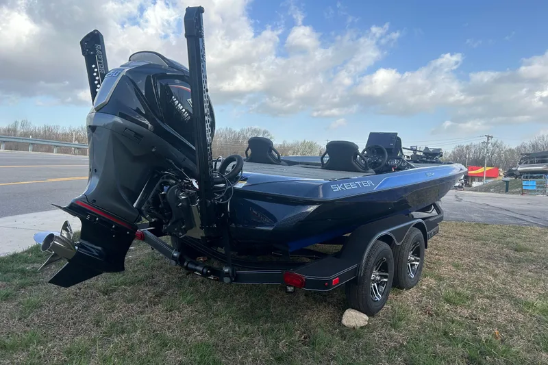 Slide: The Image of 2025 Skeeter ZXR21 boat on trailer, parked roadside under cloudy sky. - 3