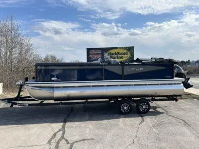 Slide: The Image of 2025 Lowe LS 230 WT pontoon boat on trailer, parked outdoors under cloudy sky. - 3