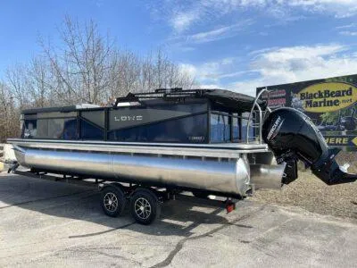 Slide: The Image of 2025 Lowe LS 230 WT pontoon boat on trailer, parked outdoors near BlackBeard Marine sign. - 6