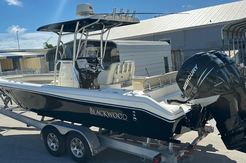 Slide: The Image of 2012 Blackwood 270 boat on trailer with Mercury Verado engines, parked outdoors. - 2