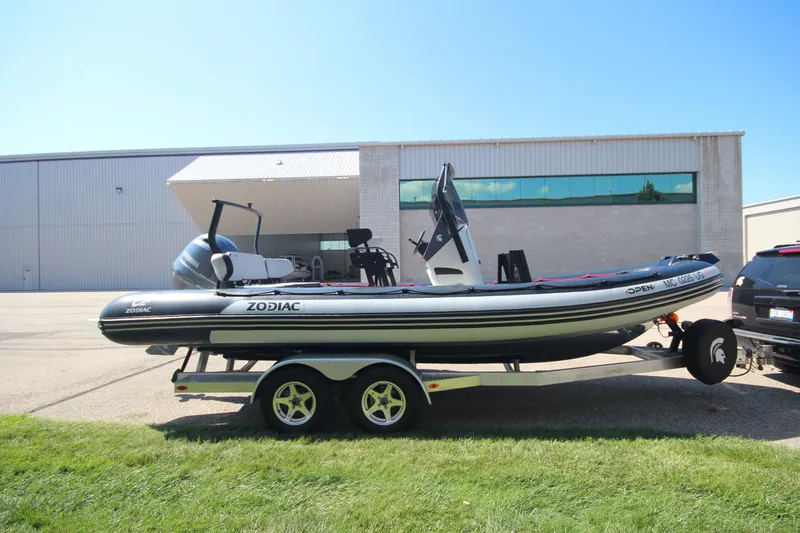 The Image of 2018 Zodiac Open 7 NEO boat on trailer, parked outdoors near a building. - 1