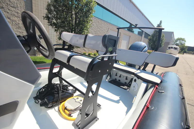 Slide: The Image of 2018 Zodiac Open 7 NEO boat interior with seating and steering wheel, parked outdoors. - 13