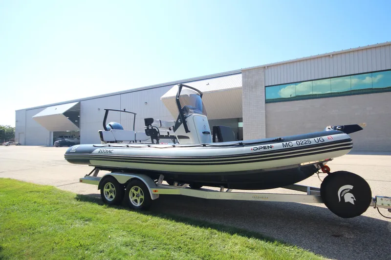 Slide: The Image of 2018 Zodiac Open 7 NEO boat on trailer, parked outside a large building. - 28