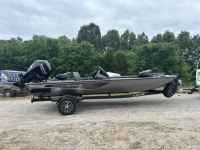 The Image of 2025 Lowe Stinger 195 Crappie boat on trailer, parked outdoors with trees in background. - 0